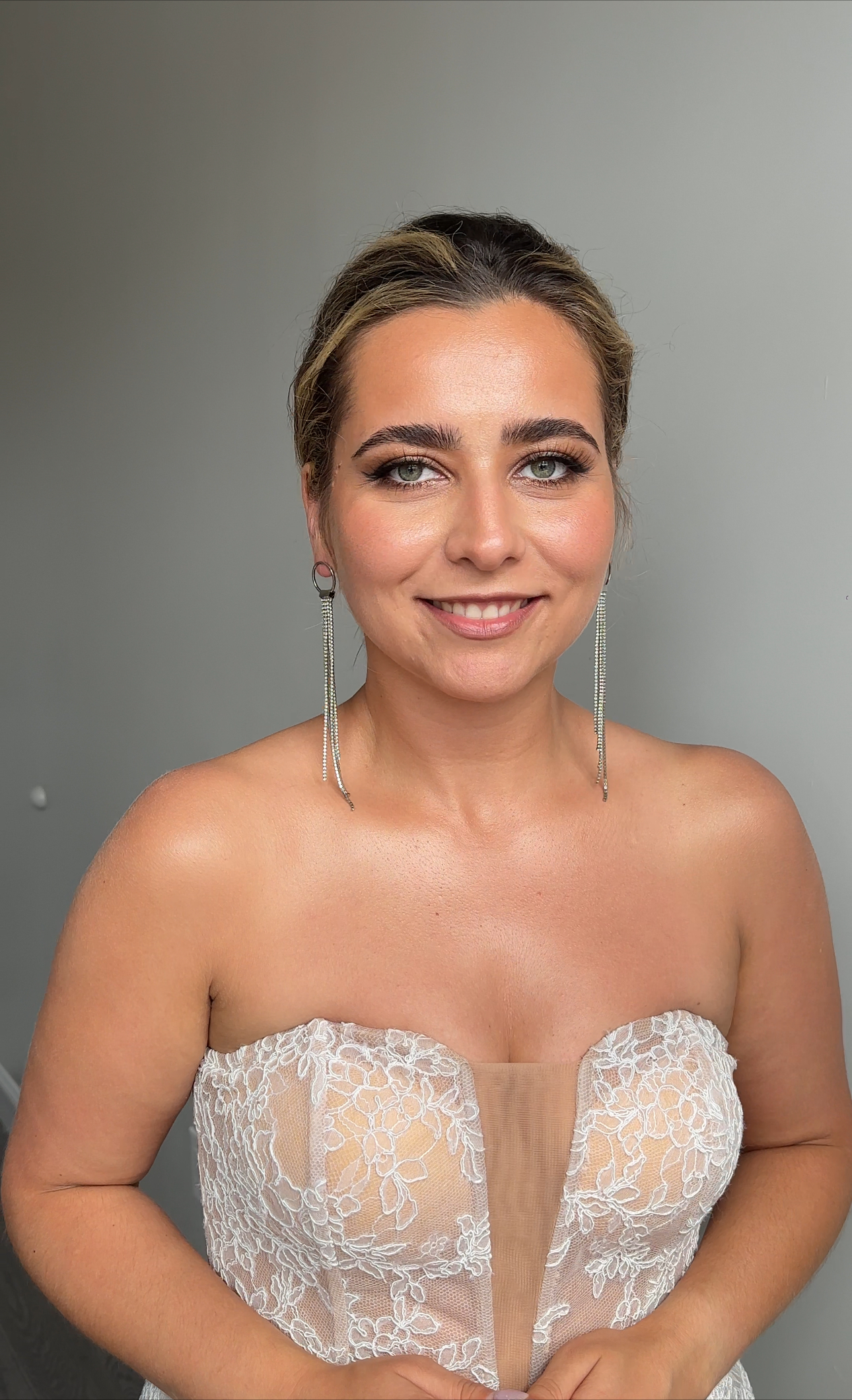 Smiling bride; fresh bridal glam; sleek low updo, statement earrings.