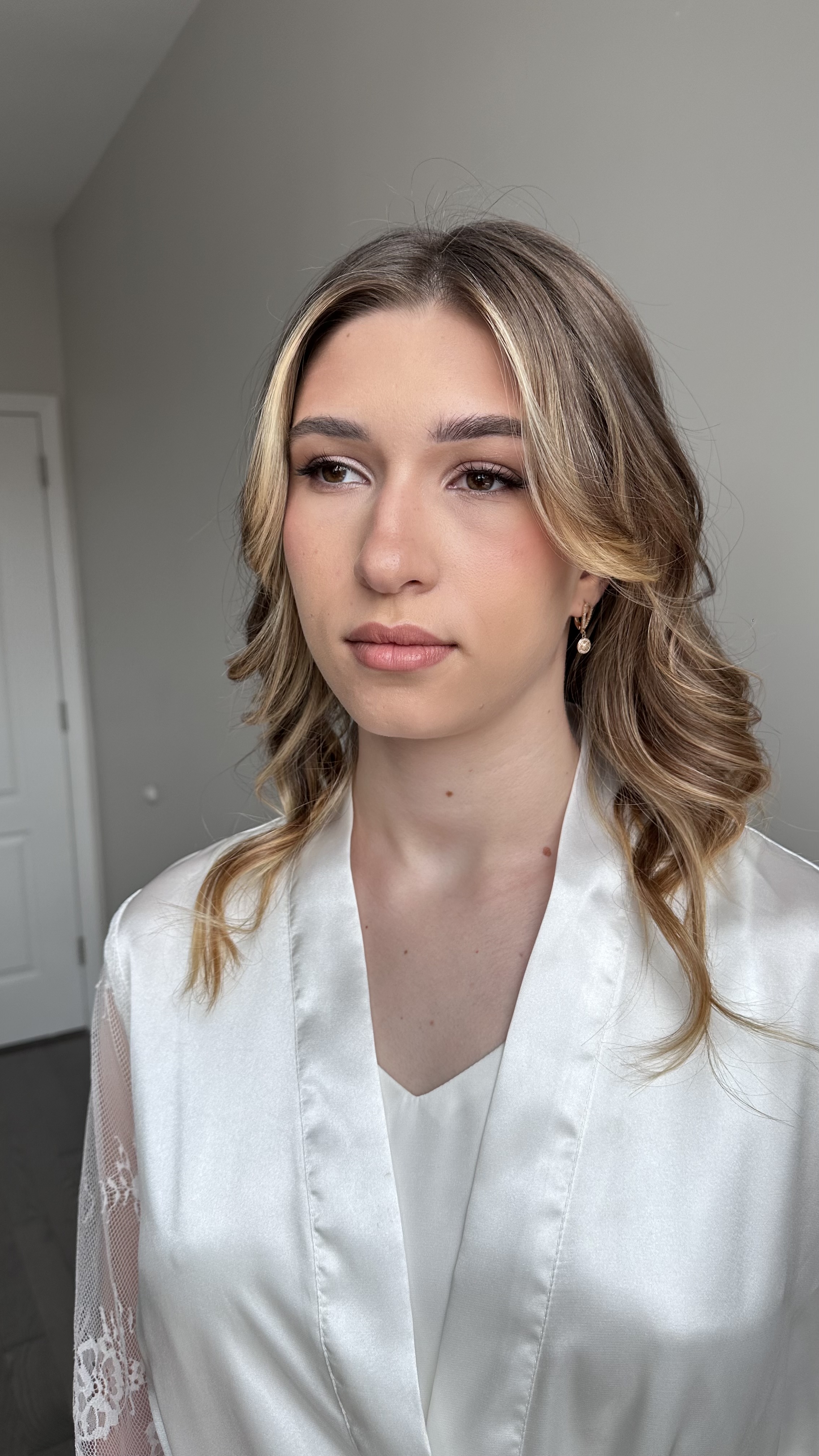 Soft curls with natural glam; rosy tones, defined lashes; loose bridal waves.