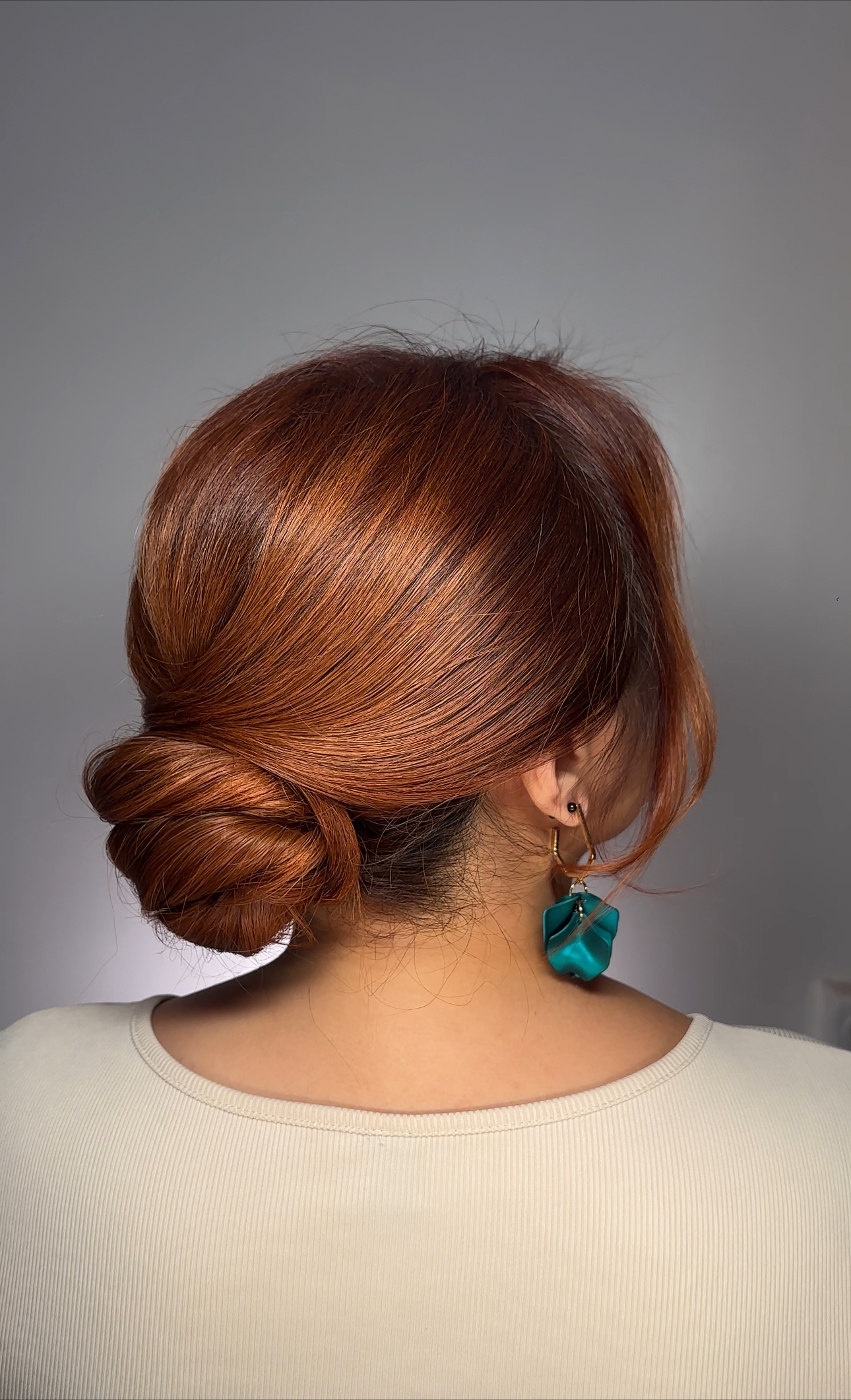 Elegant hairstyle: low bun on red hair with sleek styling.