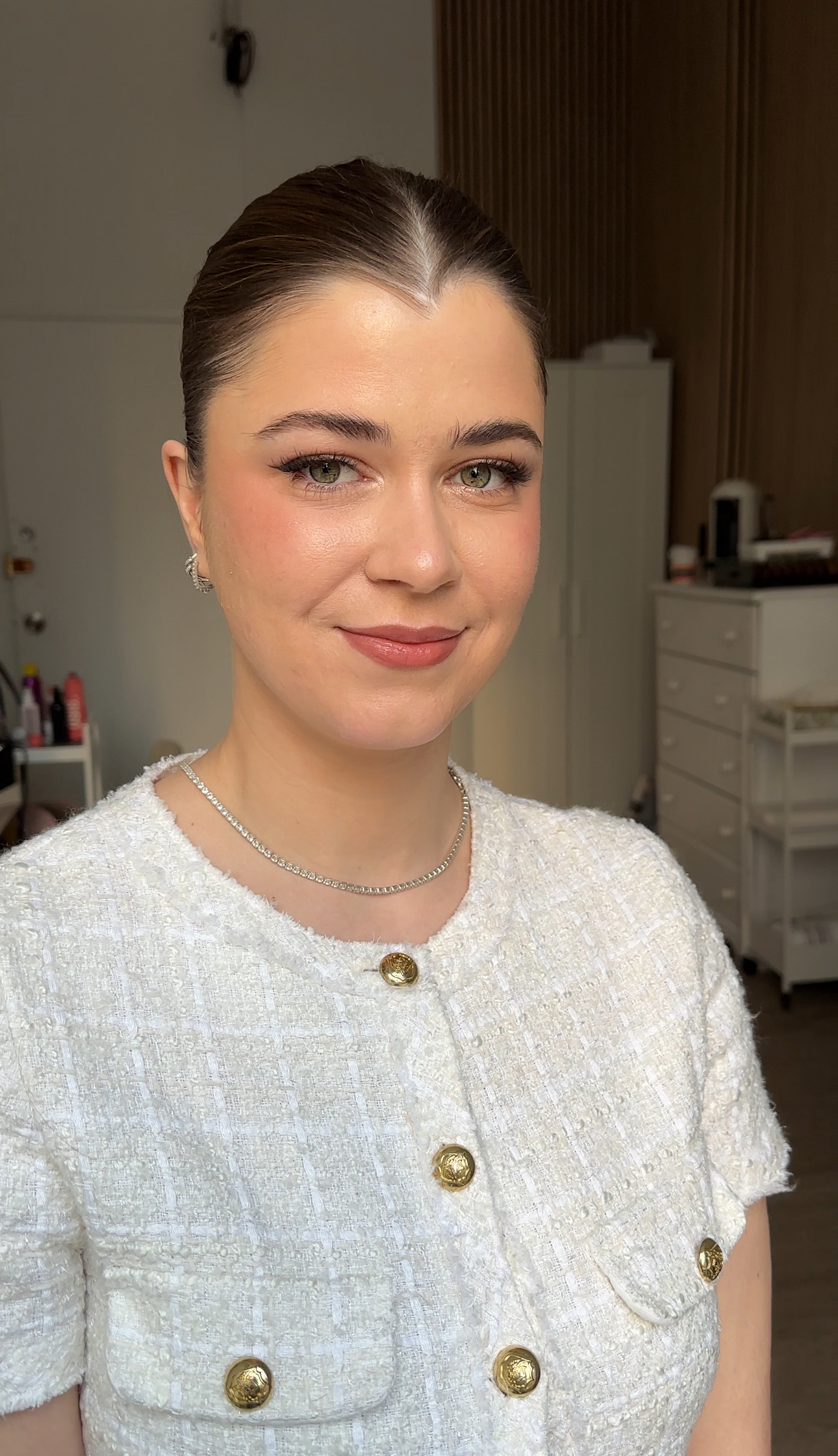 Close portrait with nude makeup; tweed jacket with gold buttons.