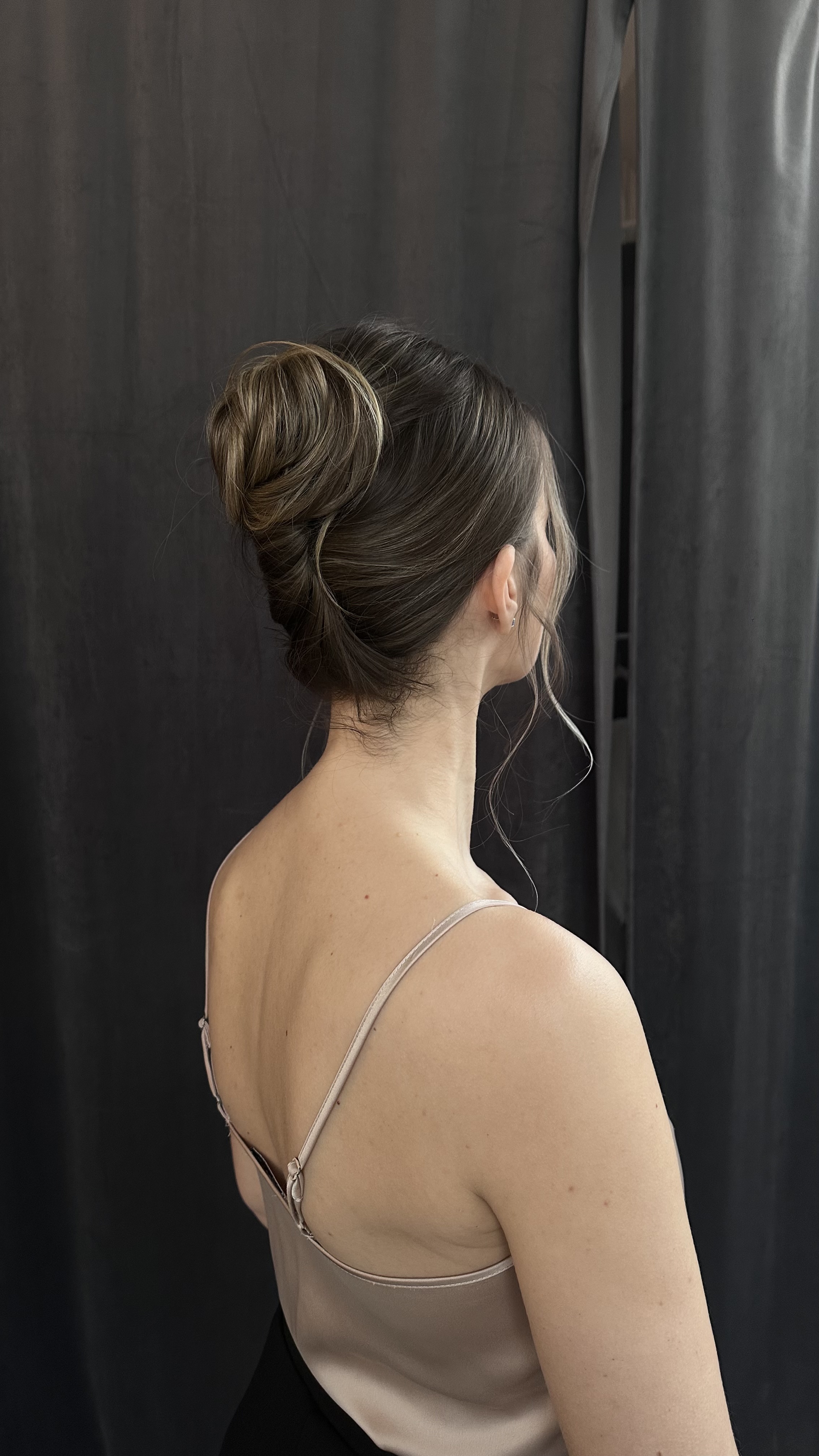 Textured low chignon close-up; soft strands, neutral background.