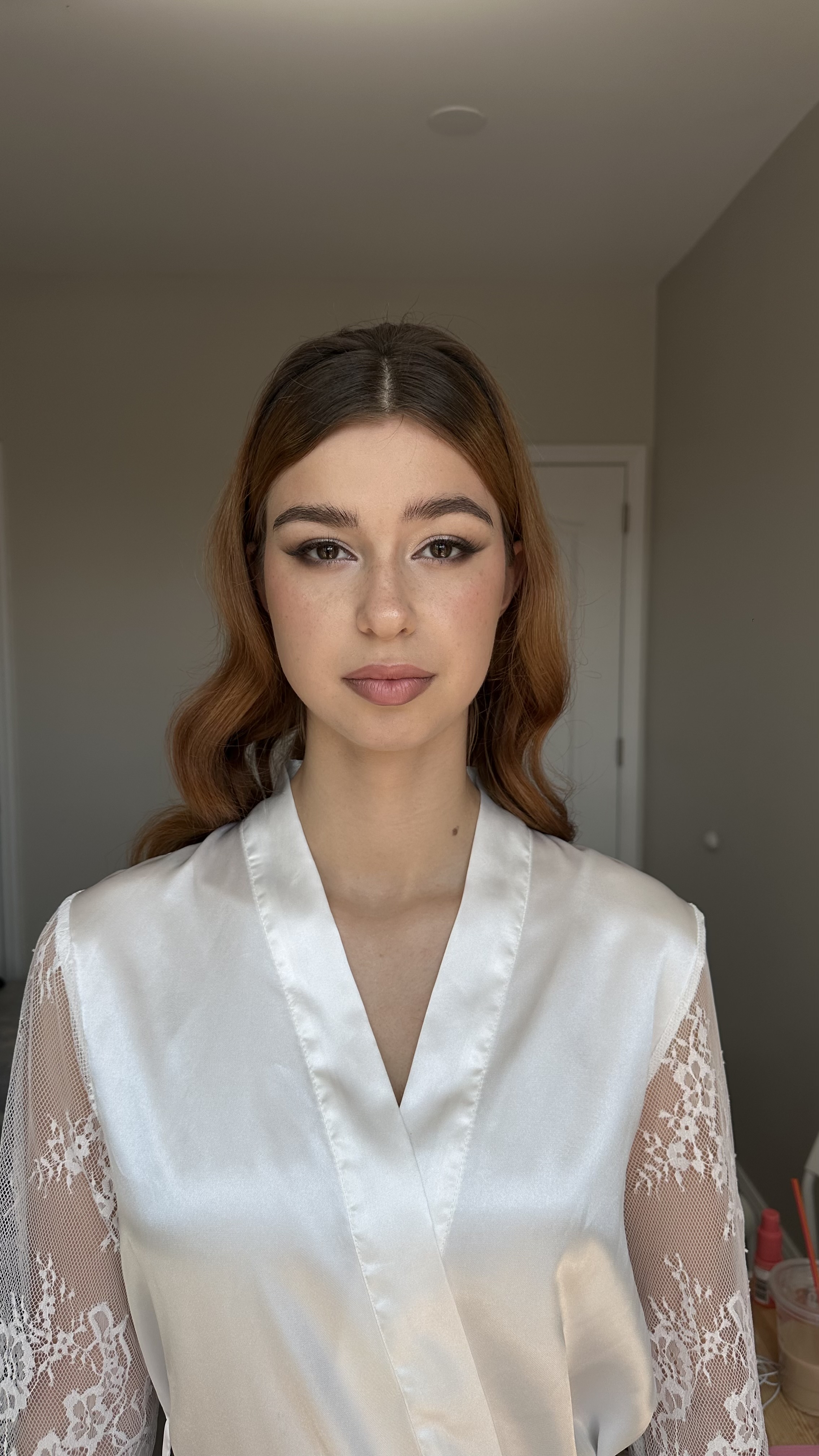 Front bridal portrait in satin robe; classic nude makeup with soft waves.