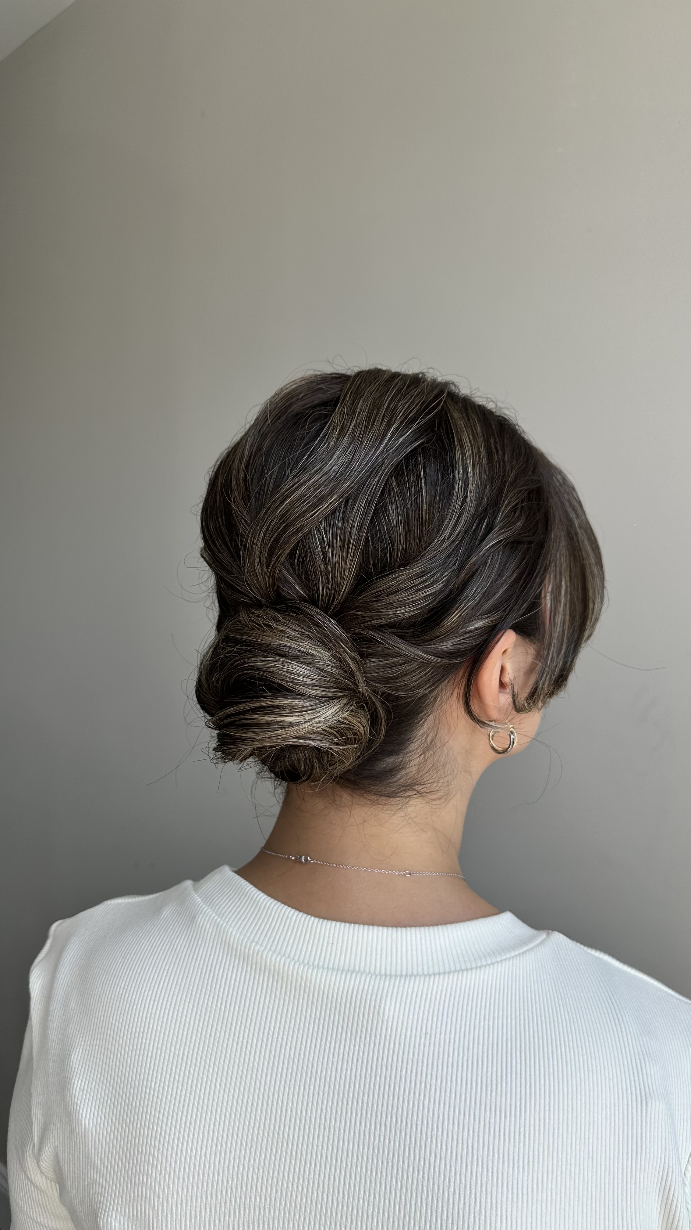 Textured low bun with soft face-framing pieces — back view.