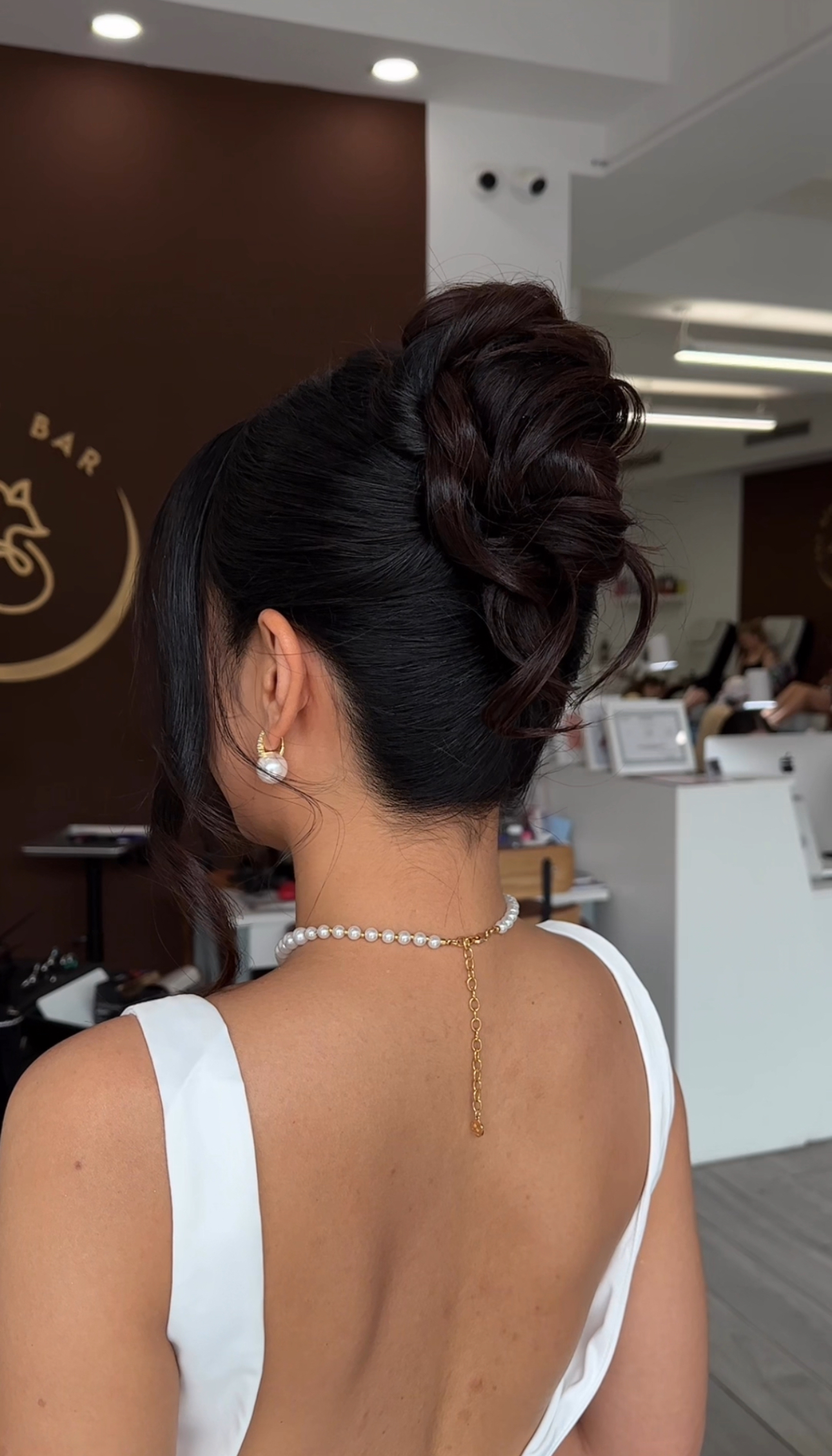 High evening updo with braid and loose waves — back view.