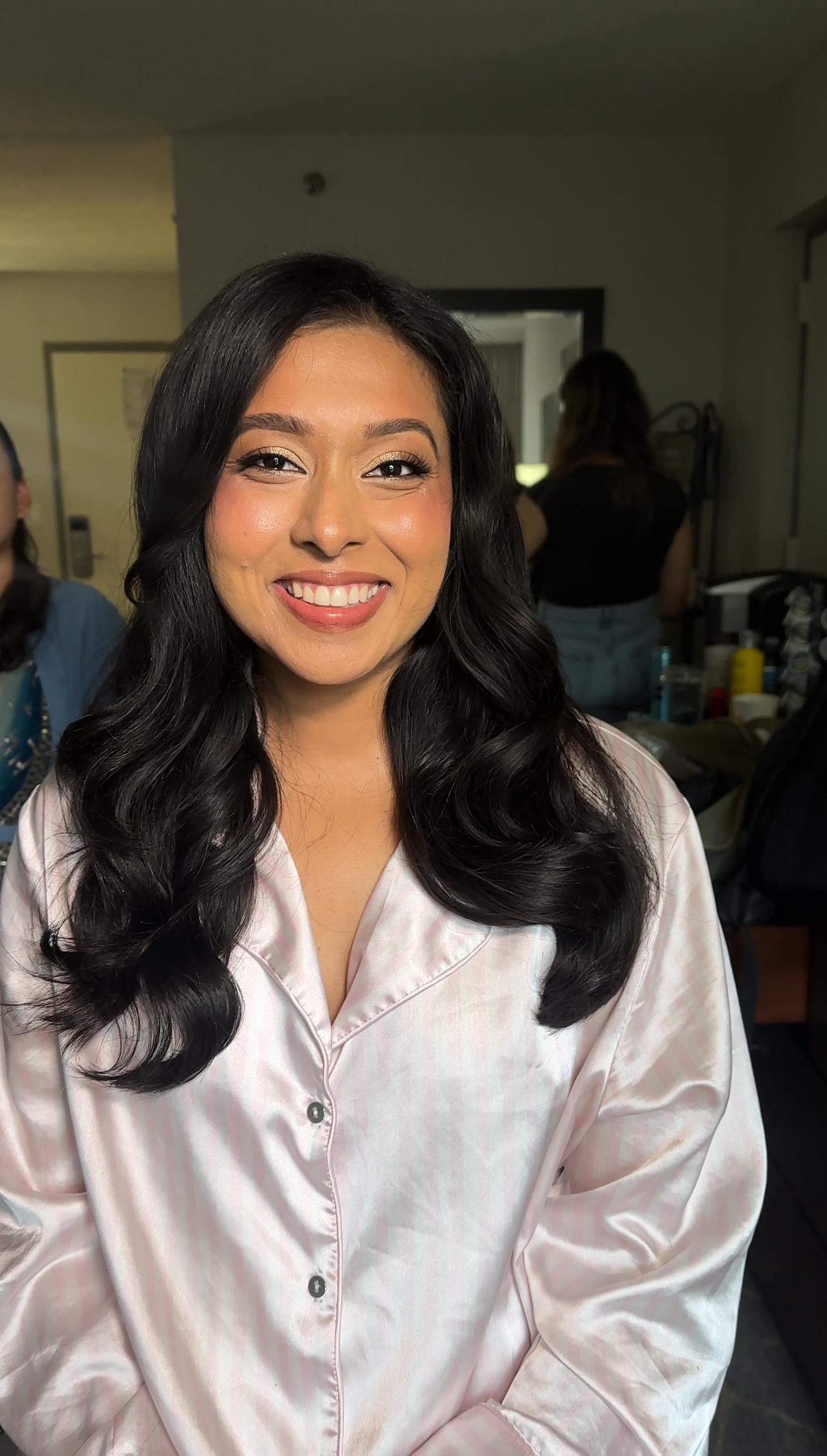 Soft-glam on medium skin: glowing base, pink blush, voluminous waves.