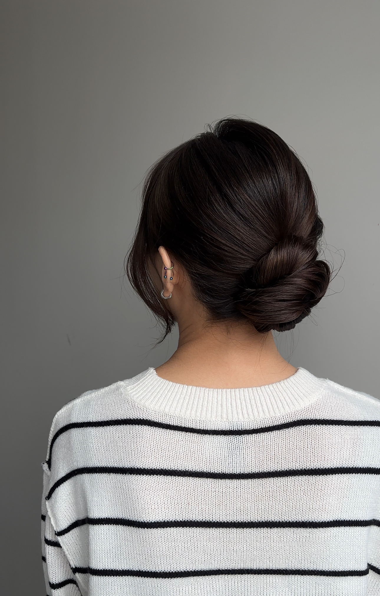 Sleek styling: low chignon on dark hair — back view.