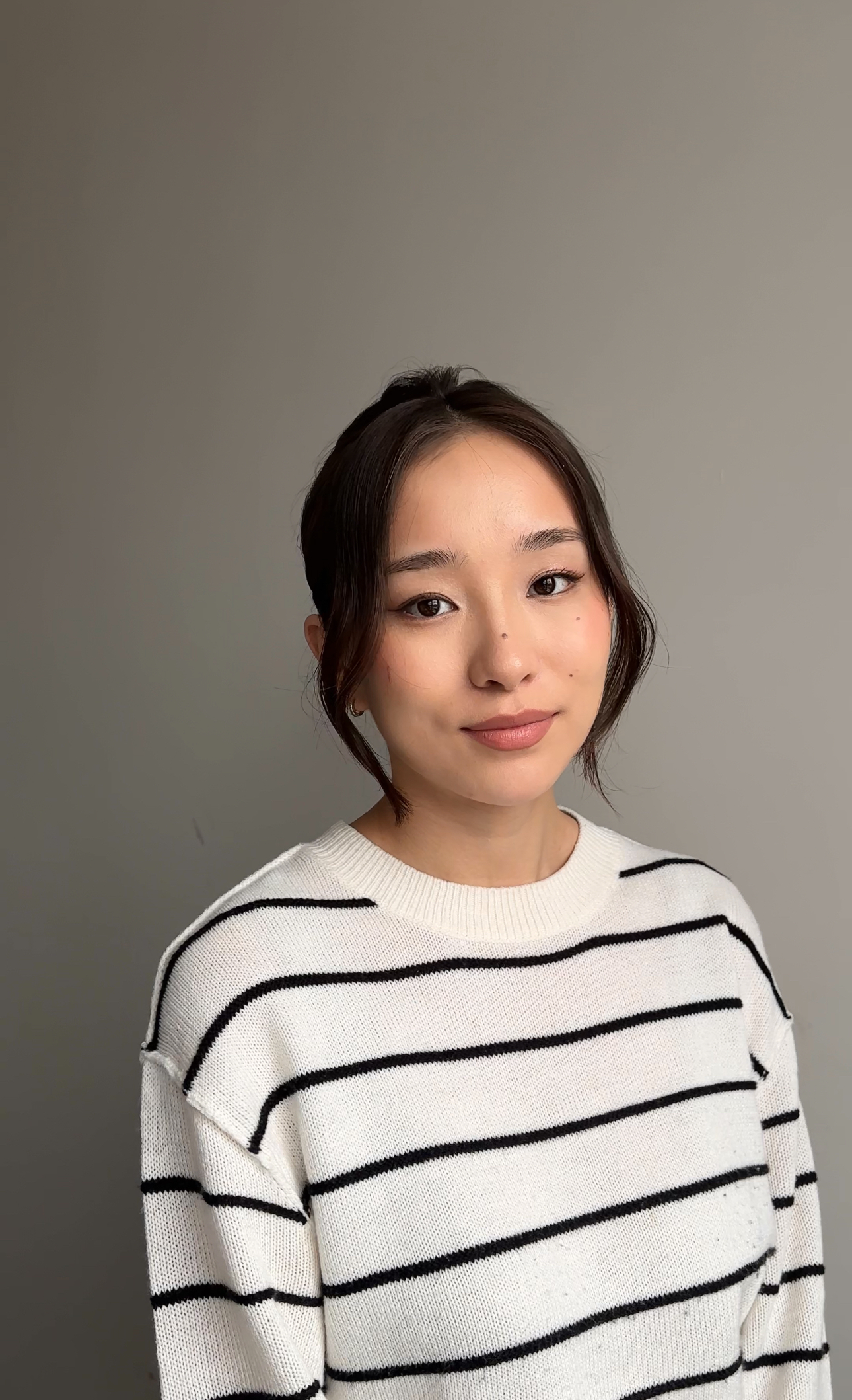 Light daytime makeup with soft winged liner; wispy face-framing strands.